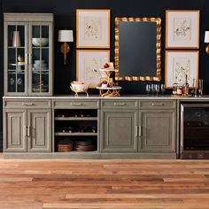 a dining room with wooden floors and black walls, gold framed pictures on the wall