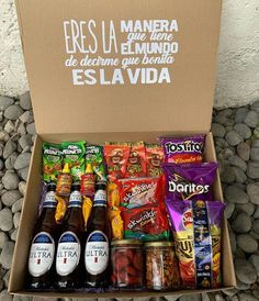 a box filled with lots of different types of food and drinks next to some rocks