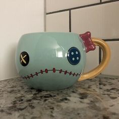 a ceramic coffee cup with a face painted on the side and a handle in the middle