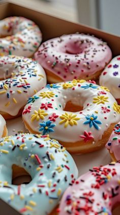 a box filled with lots of different flavored donuts covered in sprinkles