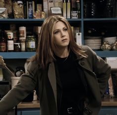 a woman standing in front of a kitchen counter with her hands on her hips and looking at the camera