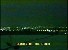 the city lights are lit up in the night sky as seen from a hill top