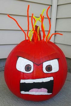 a red pumpkin with an angry face painted on it's front porch area and some orange sticks sticking out of its mouth