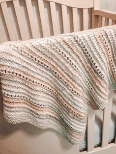 a crocheted blanket hanging from the side of a wooden slatted bench