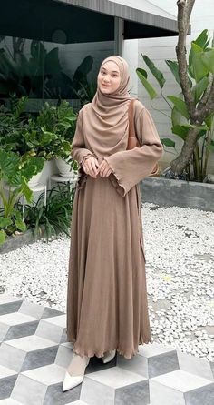 a woman wearing a hijab standing on a checkered floor in front of a building