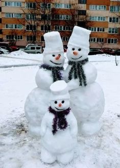 three snowmen standing next to each other in the snow