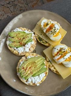 four appetizers are arranged on a plate with cheese and an avocado