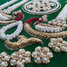 several necklaces and brooches laid out on a green cloth with gold trim