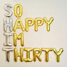 the words so happy i'm thirty spelled out in gold and silver foil balloons