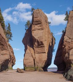 two large rocks sitting on top of a sandy beach