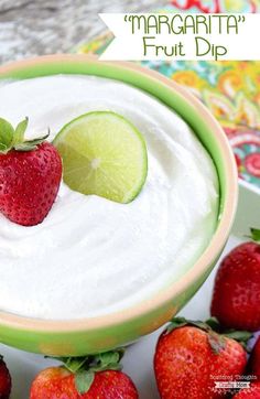 a close up of a bowl of fruit dip with strawberries and limes on the side