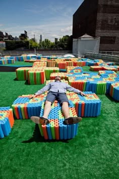 a man laying on top of a giant pile of lego blocks in an open field