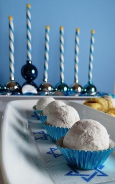 three cupcakes sitting on a plate with candles in the background and blue wall