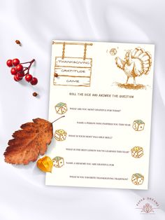 a thanksgiving card with an orange leaf and some red berries next to it on a white surface