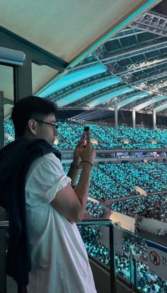 a man taking a photo with his cell phone in front of an audience at a sporting event