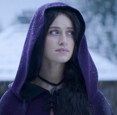 a woman wearing a purple hoodie in the snow with her eyes closed and looking off to the side