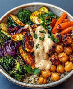 a bowl filled with vegetables and sauce on top of it's side, sitting on a blue surface