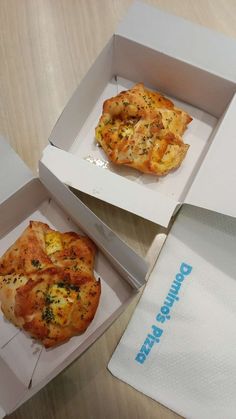 two pizzas in boxes sitting on a table