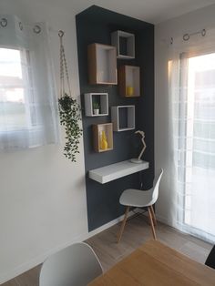 a white chair sitting in front of a wooden table next to a wall mounted shelf