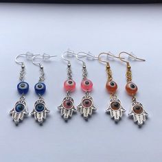 five pairs of earrings with evil eye and hamsah charms hanging from the earwires