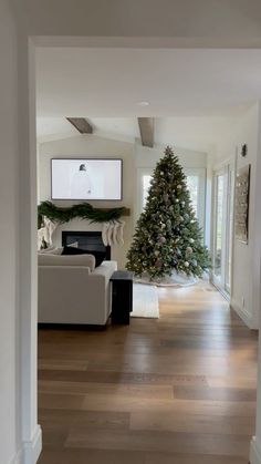 a living room filled with furniture and a christmas tree in the middle of the room