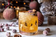 a glass filled with liquid surrounded by christmas decorations