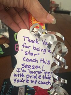 a person holding up a candy bar with writing on it and ribbons around the edges