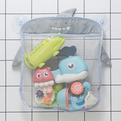 a blue mesh bag filled with toys on top of a tiled floor next to a white tile wall