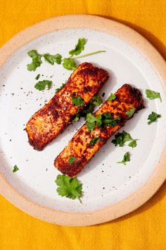 two pieces of meat on a plate with cilantro