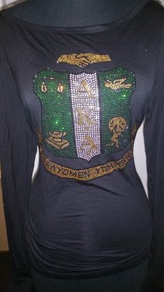 a woman's black shirt with green and gold sequins on the chest