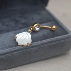 a gold and mother of pearl belly ring in a velvet case with its lid open