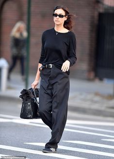 a woman in black is walking down the street