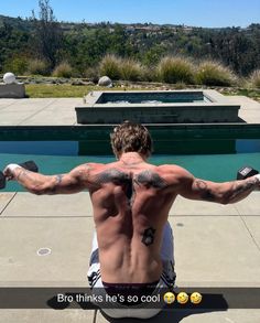 a man sitting on top of a bench with his back turned to the camera, holding two dumbbells