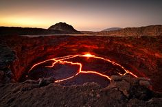 the inside of a crater with lava and bright lights in the dark, surrounded by mountains