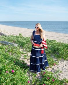 a woman in a blue dress standing on the beach