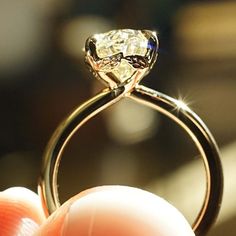 a close up of a person's hand holding a ring with a diamond on it