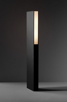 a tall black lamp sitting on top of a table next to a white light bulb