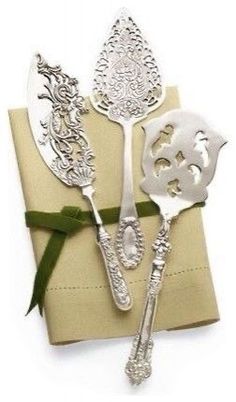 two silver spoons sitting on top of a napkin with a bow around it's neck