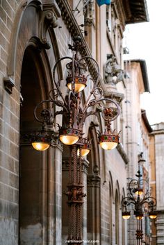 an old fashioned street light hanging from the side of a building with lights on it