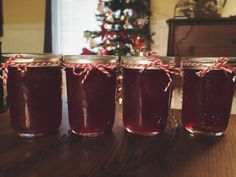 four jars filled with liquid sitting on top of a table next to a christmas tree