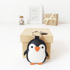 a penguin keychain sitting on top of a box next to a small gift