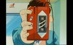 a person holding up a cell phone in front of their face with an anime character on it