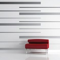 a red chair sitting in front of a white wall with horizontal lines on the wall