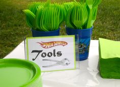 green plastic utensils are sitting on a table with a sign that says tools