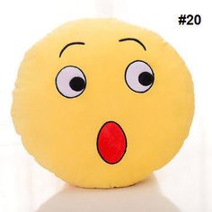 a yellow round pillow with a surprised face on it's side, sitting on a white surface