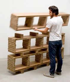 a man standing in front of a shelf filled with wooden boxes and shelves that are stacked on top of each other