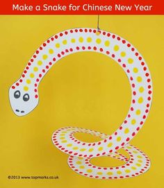 a paper snake hanging on a yellow background with the words make a snake for chinese new year