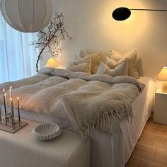 a bed with white linens and pillows in a bedroom next to a large window