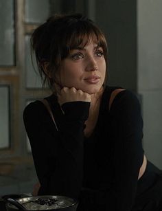 a woman sitting at a table with a bowl of food in front of her face