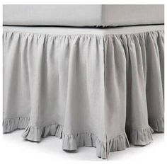 the bed skirt has ruffles on it and is made from light gray linen